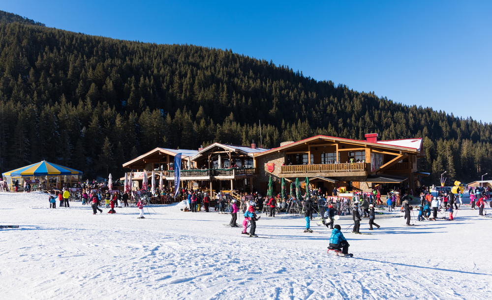 Bansko ski station, Kolarski ski lift at Banderishka polyana, skiers on ski slopes, mountain. With pine trees, people. Snow