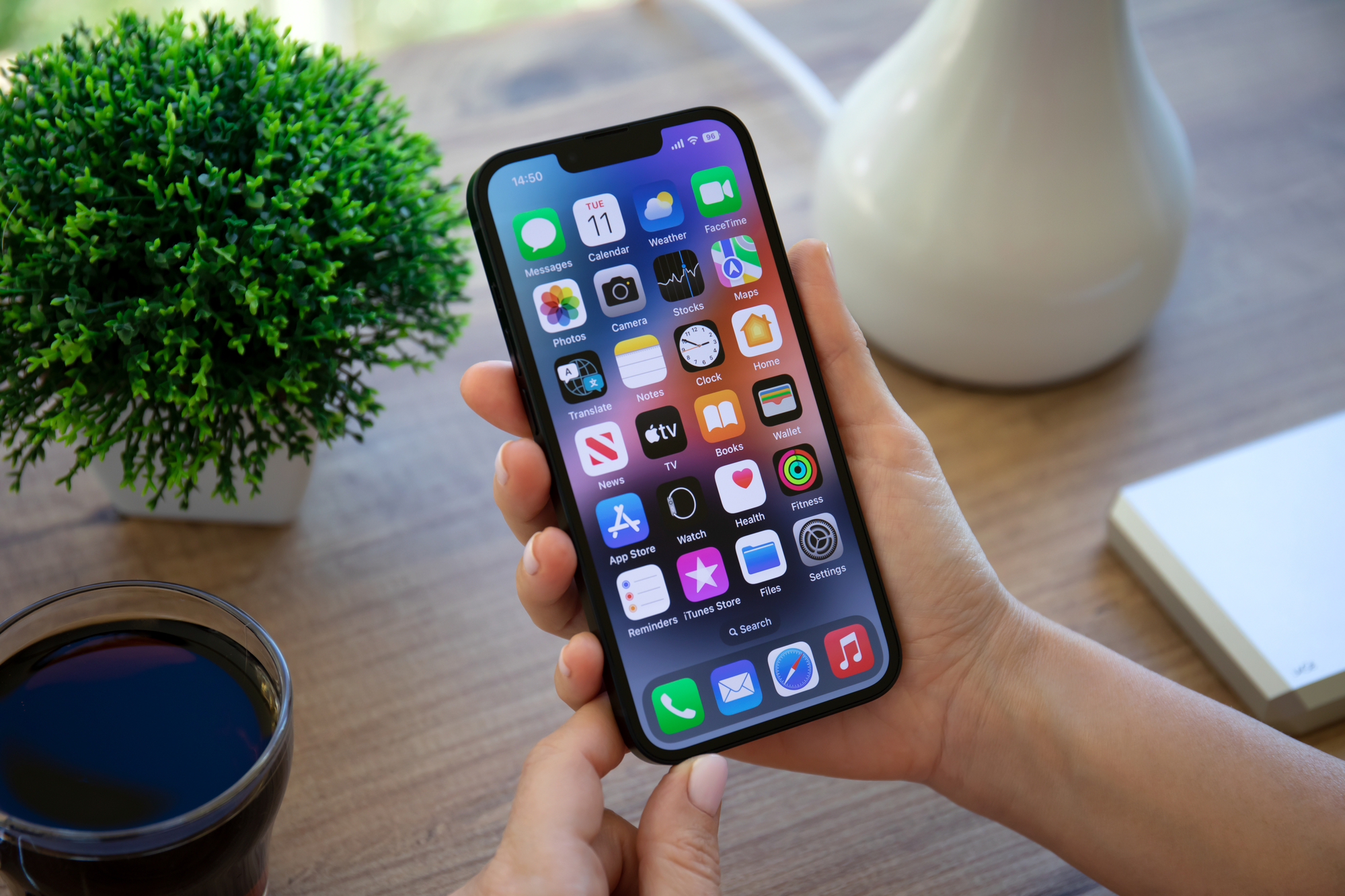 Woman hand holding iPhone 14 with home screen IOS 16 on the screen